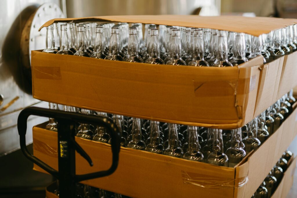 Stacks of empty glass bottles in a factory for beverage production and packaging.