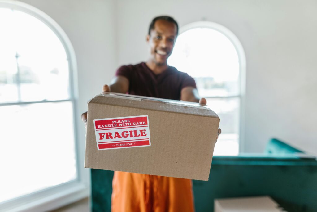 A person holding a cardboard box labeled fragile, signifying careful handling during a move.